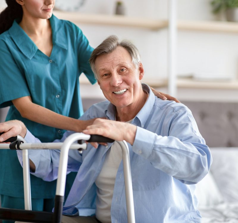 disabled-senior-man-receiving-medical-assistance-from-young-caregiver-at-home-copy-space.jpg